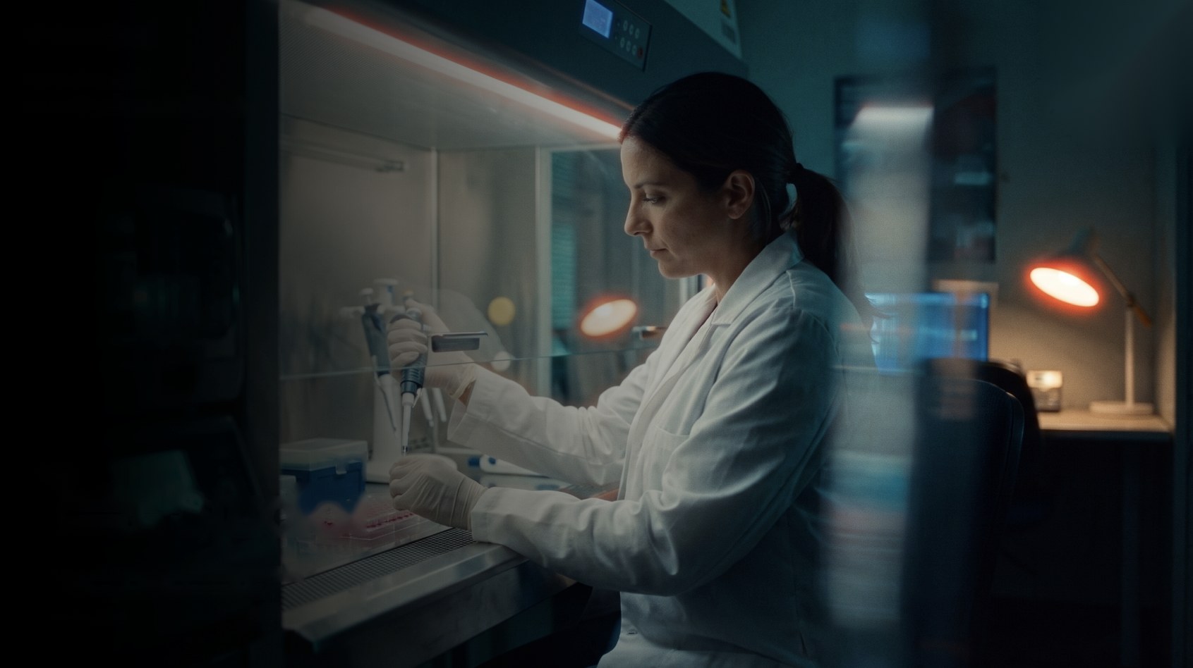 A scientist at a lab bench in low evening light